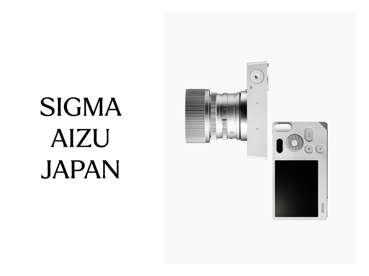 Fotocamera SIGMA BF color argento con obiettivo, accompagnata dalla scritta “SIGMA AIZU JAPAN” su sfondo bianco.